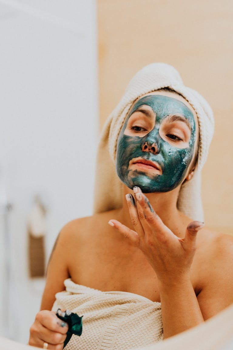 A woman applying a cosmetic face mask at home for skincare and relaxation.