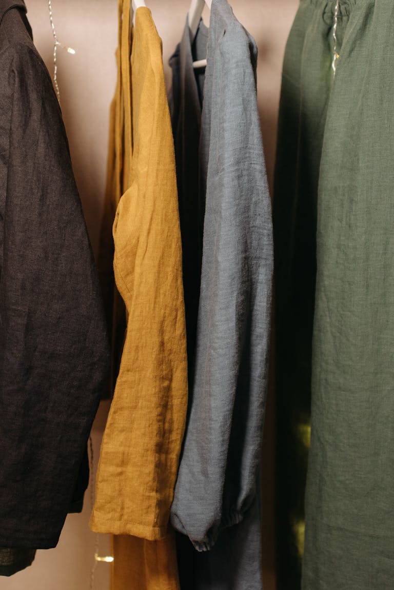 Linen clothes in various colors hanging neatly in a closet display.