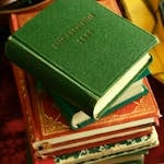 Vertical shot of a stack of colorful vintage books focusing on a green one.