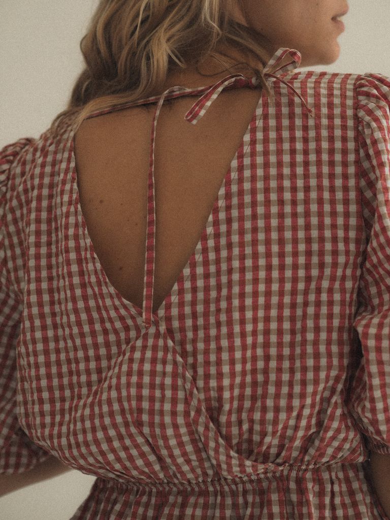 A close-up of a woman wearing a backless plaid dress, showcasing fabric pattern.