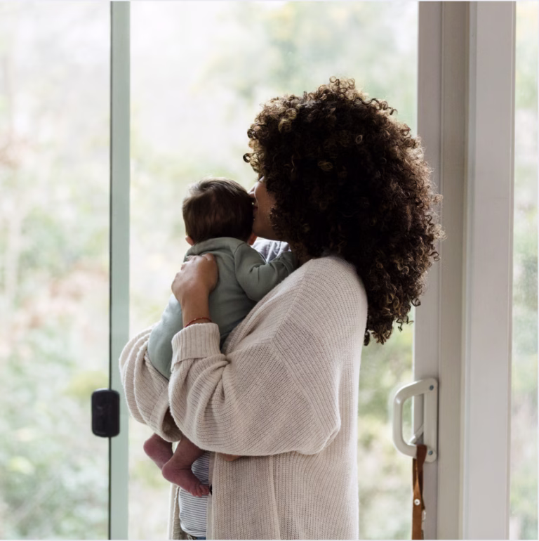 new mother stnading and holding her baby looking out a window