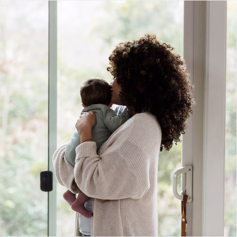 new mother stnading and holding her baby looking out a window