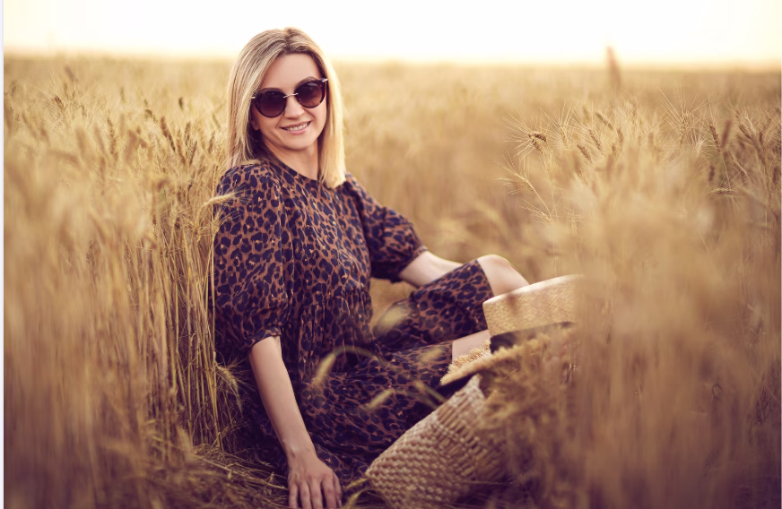woman in a field in the fall wearing a leopard print top