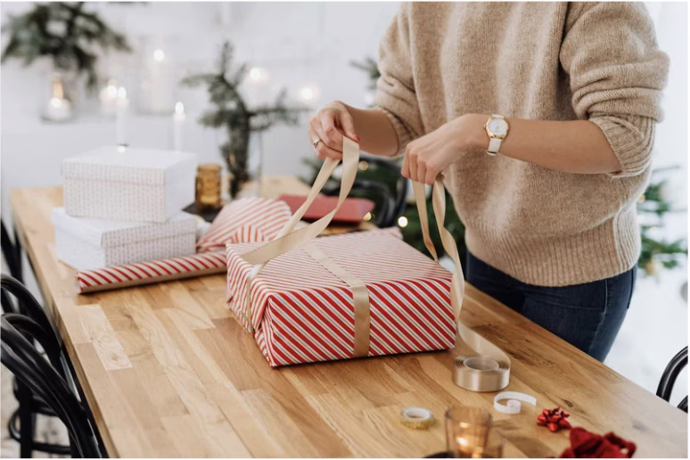 woman wrapping a gift at her kitchen table
