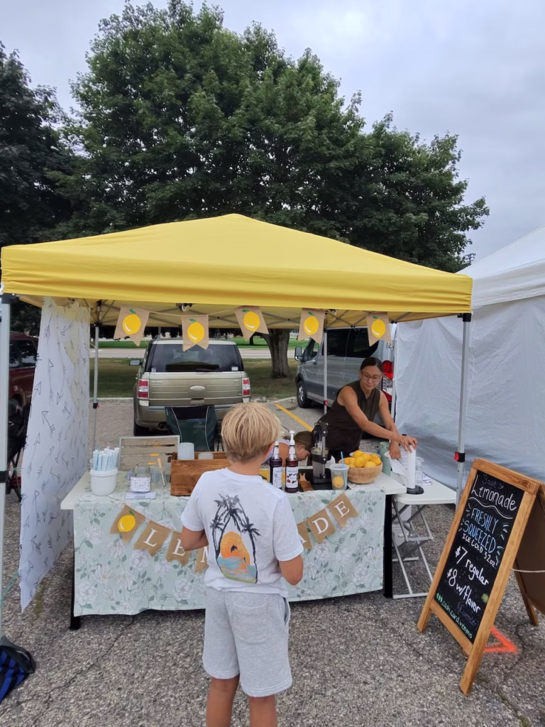 boy in front of lemonade stand at local farmers market