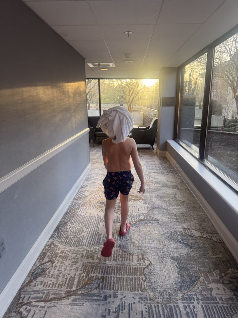 boy in hallway after swimming with towel on his head