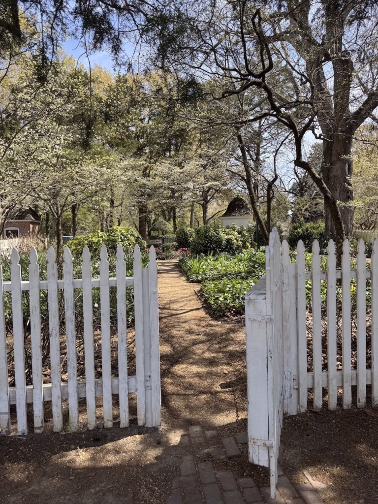white picket fence leading to gardens