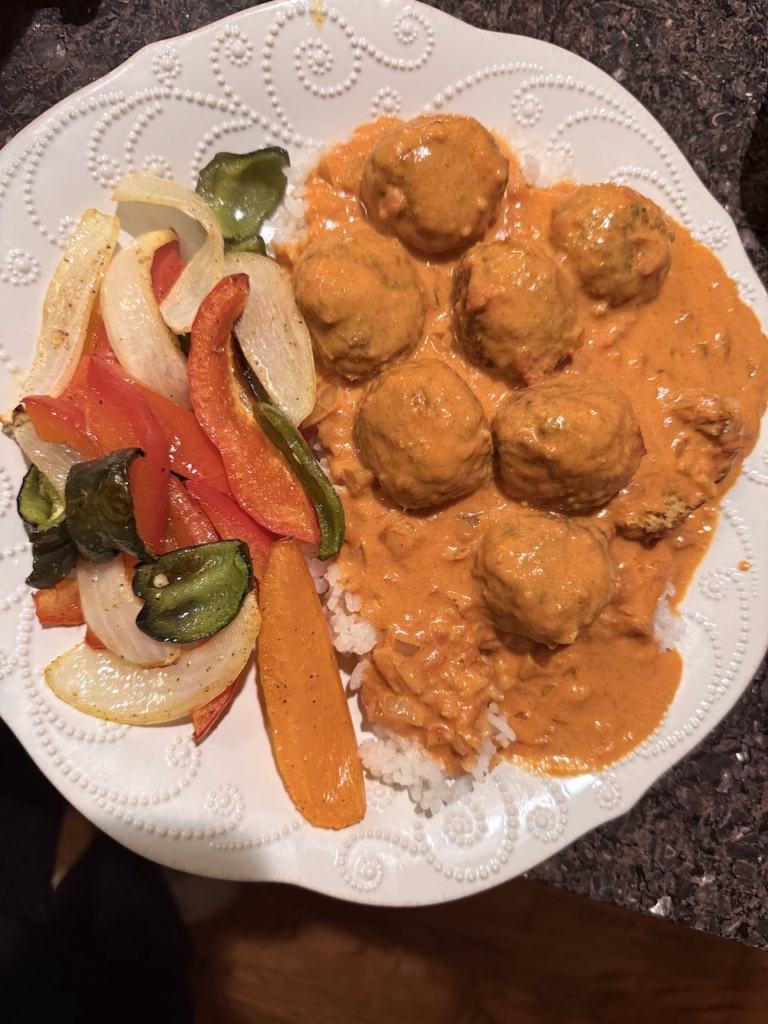 butter chicken meatballs served over rice with a side of roasted vegetables