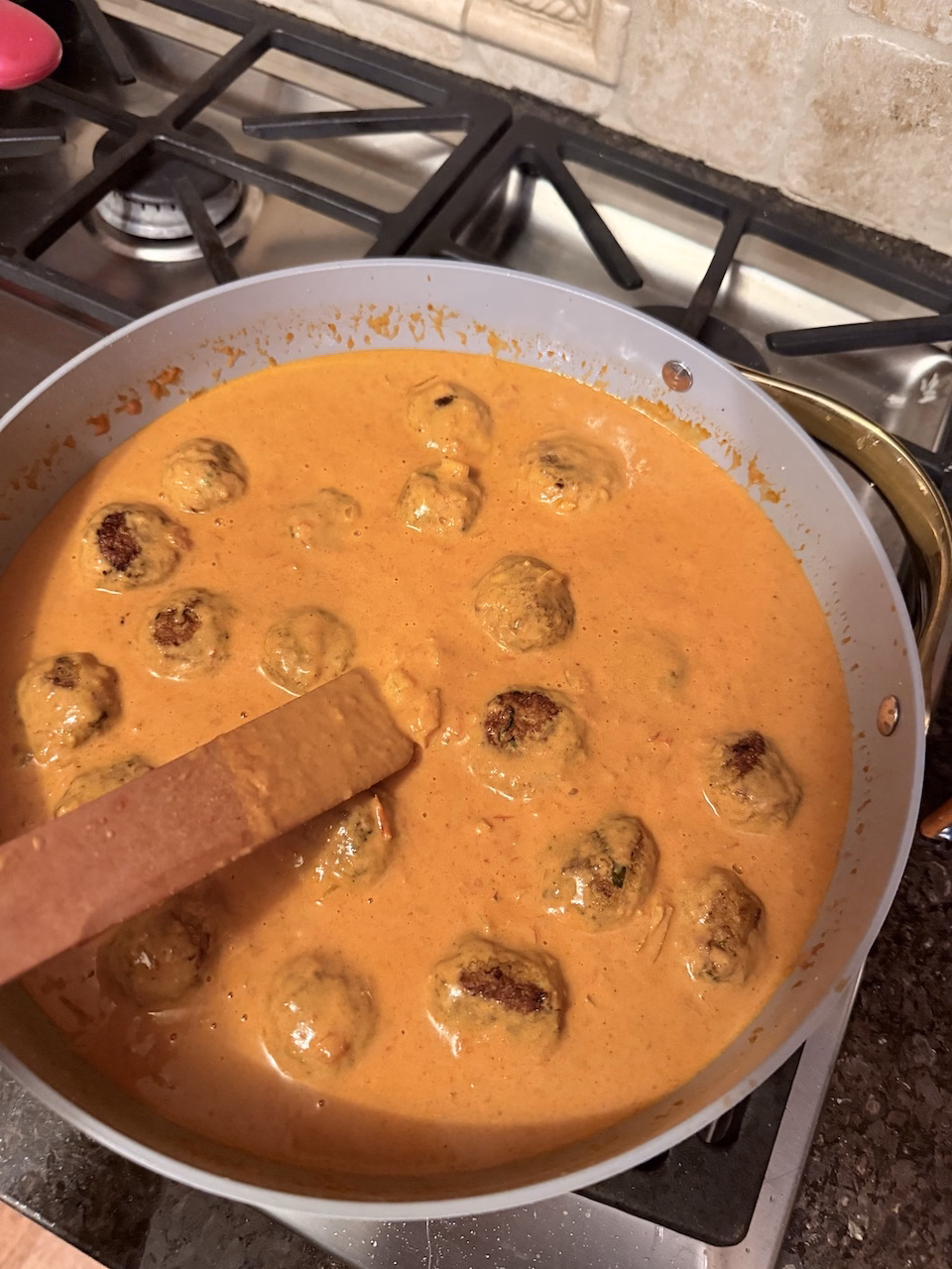 meatballs simmering in butter chicken sauce